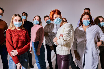 young people in medical face masks during Covid second wave outbreak confidently posing at camera. people isolated in studio, portrait