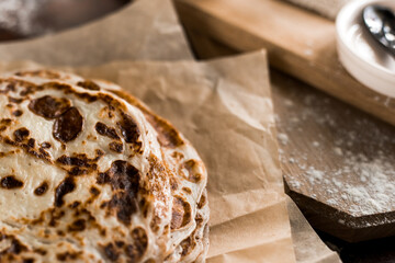 A stack of buttered crepes on a pan. Shrovetide or pancake week. Home cuisine. Ruddy toasted pancakes lie on parchment paper