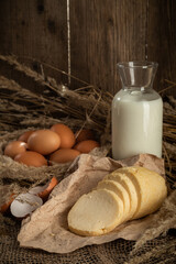 homemade cheese on craft paper next to milk and chicken eggs.