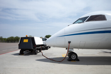 Airplane connected to Ground Power Unit. Plane on airfield. Side view