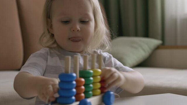 Little girl playing wooden education games on the table. Sorting rainbow wheels. Handheld Close Up Shot.