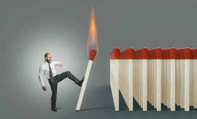 businessman kicking a lit match to ignite a chain reaction.