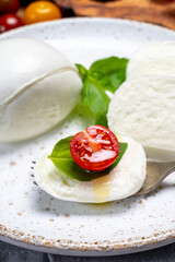 Cheese collection, eating. of white soft Italian cheese mozzarella, served with red cherry tomatoes, fresh basil leaves