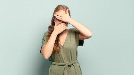 blonde pretty woman covering face with both hands saying no to the camera! refusing pictures or...