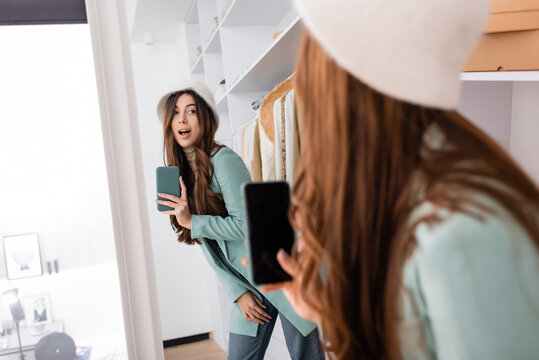 Woman taking photo on smartphone while looking at mirror in wardrobe