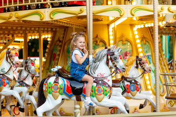 Fototapeta na wymiar happy girl in an amusement park rides a horse on a carousel in the summer