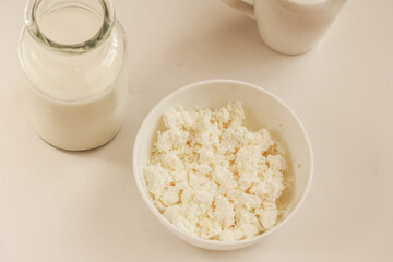 Organic cottage cheese in white bowl and jar of milk on white background.  Bio/organic/natural ingredient.  Dairy products. Isolated,  copy space