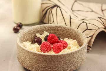 Natural cottage cheese, berries in a ceramic bowl on grey background. Bio, organic, natural ingredient. Healthy and tasty eating. Selective focus