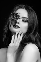 girl brunette green make-up eyes gaze on black pink background black and white close portrait with brown spider on face tarantula