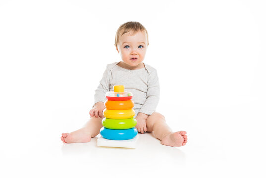 baby girl sitting on floor playing with toy isolated on white background.