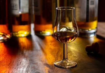 Dram of single malt scotch whisky and bottles on background