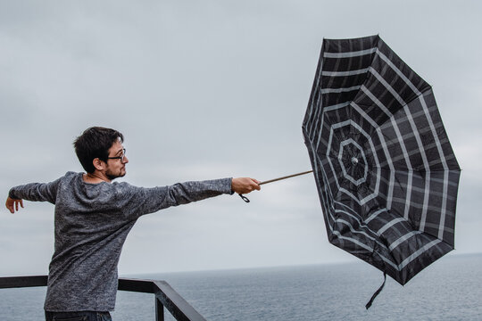 Young Man With An Umbrella Turned Around By The Wind