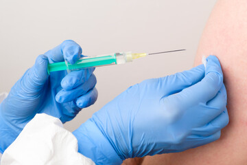 A doctor or nurse in rubber gloves gives a shot or injection. Vaccination against coronavirus, SARS-Cov-2.