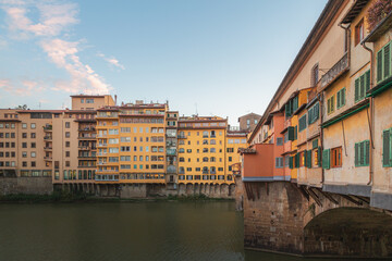 Fototapeta na wymiar The historic and popular tourist attraction Ponte Vecchio bridge perched over the River Arno in Florence, Italy on a clear sunny day in Tuscany.