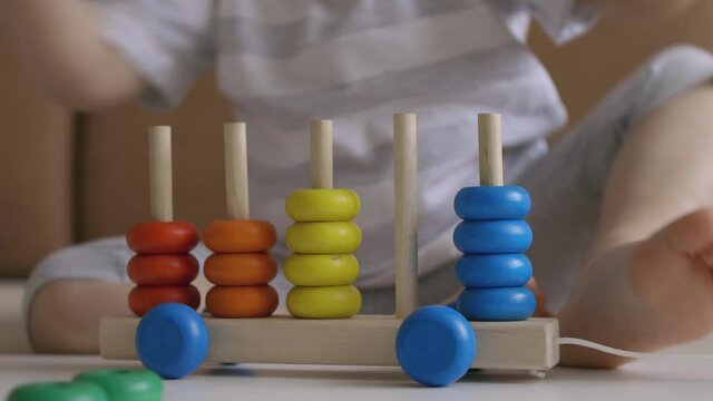 Little girl playing wooden education games on the table. Sorting rainbow wheels. Handheld Close Up Shot.