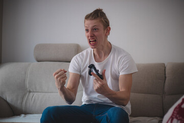 young e-sports player rejoices in winning a game against an opponent online. Caucasian white man...
