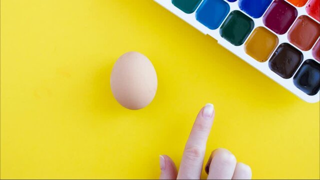 Creative finger painting easter eggs with red and blue paint, stop motion animation on yellow background