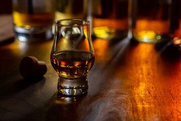 Dram of single malt scotch whisky and bottles on background