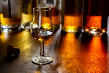 Dram of single malt scotch whisky and bottles on background
