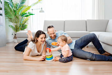 happy mother and father with baby daugter playing at home