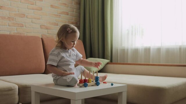 Little girl playing wooden education games on the table. Sorting rainbow wheels. Medium shot.