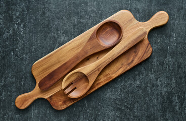 Wooden spoons on cutting boardfrom wood on gray background, top view, closeup. Kitchen utensils