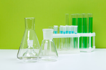 Various laboratory glass items with water and empty on white table with green background