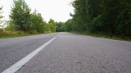 Fototapeta na wymiar Asphalt gray road among greenery low plan