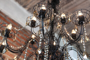 chandelier made of black wire with candle light bulbs and glass pendants. Selective focus, background
