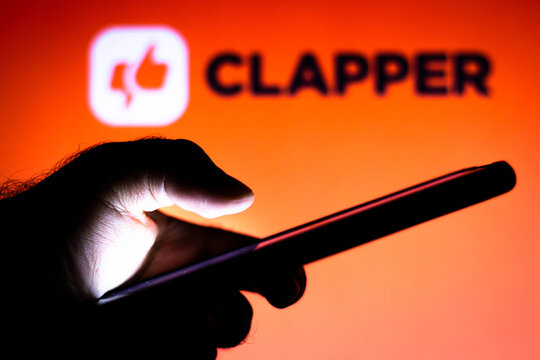 February 2, 2021, Brazil. In this photo illustration the Clapper logo seen in the background of a silhouette hand holding a mobile phone.