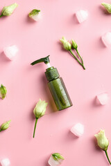Natural organic lotion with ice cubes and flowers on pink background. Flat lay, top view. Beauty and SPA concept
