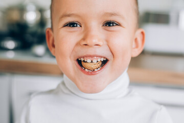 A boy child tries to crack a walnut showing healthy strong baby teeth