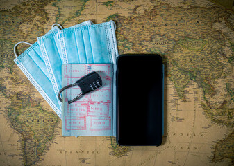 Locked passport with protection masks and phone,on the world map background