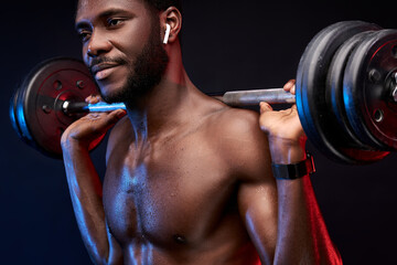 bodybuilder training with weights and listen to music in wireless headphones, enjoy sport isolated...