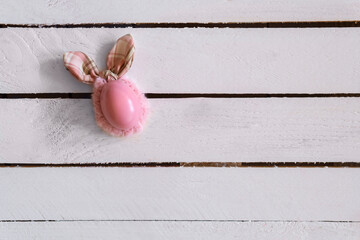 Pink easter egg with bunny ears on white wooden background. Minimal, creative concept. Flat Lay.