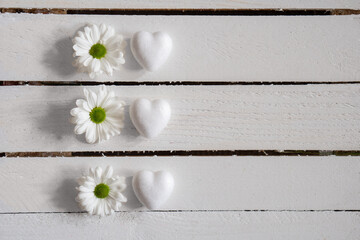 White flowrs and hearts on wooden background. Concept and idea symbol for love, spring and Mothers day. Minimal, flat lay.