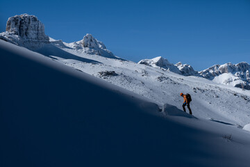 Fototapeta premium Extreme winter sports: The mountaineer reaches a snowy peak in the Alps. Concepts: determination, success, strength.