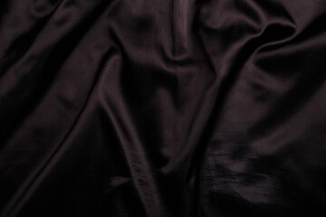 Fototapeta premium Suit or jacket lining, black shiny smooth wrinkled fabric texture, background or backdrop.