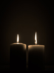 Fototapeta na wymiar two candles burning in dark