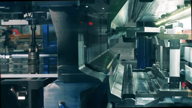 Side view of an industrial machine shearing and bending metal