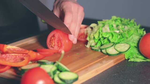 Chef in Blach Uniform is Cutting Vegetables at Home. Cook is Preparing Ingredients for Something Dietary. Healthy Food Concept. Dynamic Closeup Shot