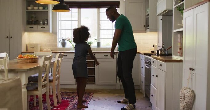 African american daughter and her father dancing together in kitchen