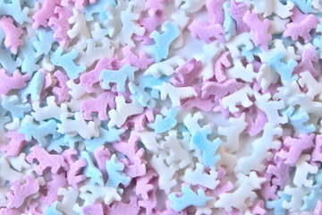 Obraz premium Delicious sugar candy unicorns in red, blue and white as sweet cake decoration and birthday topping with little horses and unicorn sprinkles as delicious background for confection frosting of donuts