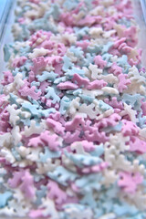 Delicious sugar candy unicorns in red, blue and white as sweet cake decoration and birthday topping with little horses and unicorn sprinkles as delicious background for confection frosting of donuts