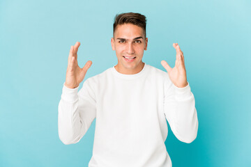 Fototapeta premium Young caucasian handsome man isolated receiving a pleasant surprise, excited and raising hands.