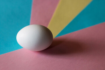 Easter concept. White egg on a multicolored background in pastel colors. The chicken laid the egg. Natural organic homemade products. Happy Easter card with copy space for text.
