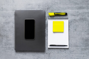 Laptop, phone, and office supplies on a gray concrete table. Workplace. A study table. Remote work. Distance learning. uminous yellow and extremely gray. The color of 2021. Copy space