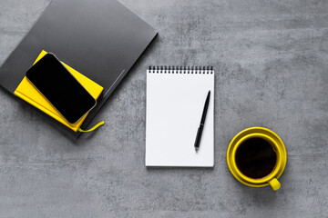 Laptop, phone, and office supplies on a gray concrete table. Coffee in a yellow cup. Workplace. Remote work. Distance learning. uminous yellow and extremely gray. The color of 2021. Copy space