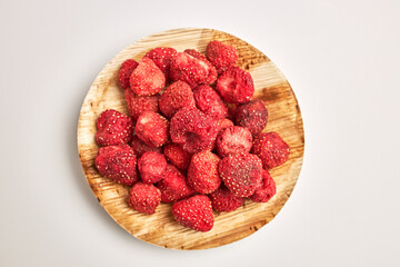 Close-up of dehydrated strawberries in wooden bowl isolated on white background.