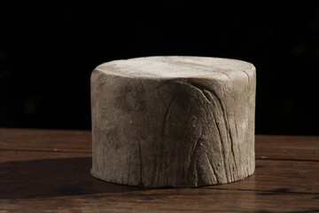 Whole caerphilly cheese on a wooden board with a black background